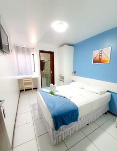 1 dormitorio con 1 cama grande y pared azul en Pousada Quaraçá Maceió, en Maceió