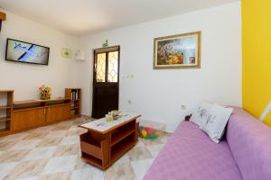 a living room with a purple couch and a table at Apartments Alice Green Oasis - in Poreč
