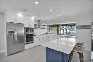 uma cozinha com armários brancos e electrodomésticos de aço inoxidável em Tropical Escape - Heated Pool - Game Room em Hollywood