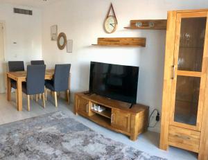 a living room with a television and a table with chairs at Fin Albir Playa in Albir
