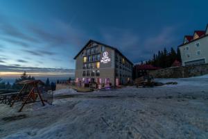 Un bâtiment avec un panneau dans la neige dans l'établissement Montis Hotel & Spa, à Muntele Mic