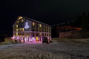 a building with a sign on the side of it at night at Montis Hotel & Spa in Muntele Mic