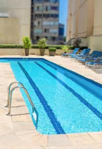 una piscina con sillas azules junto a un edificio en Ótima Localização, reformado e com piscina!, en Río de Janeiro