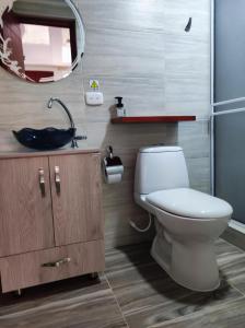 a bathroom with a toilet and a sink and a mirror at Hotel Campo Verde in Villagarzón