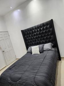 uma cama grande com uma cabeceira preta num quarto em Departamentos L em Cuauhtémoc