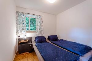 a bedroom with a bed with blue sheets and a window at Chata U Tří lišek - na samotě u lesa 