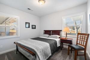 ein Schlafzimmer mit einem Bett und einem Stuhl sowie zwei Fenstern in der Unterkunft Sunset 1 in Boise