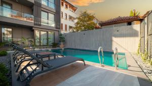 una piscina con 2 sillas junto a un edificio en VESTA SUITES en Antalya