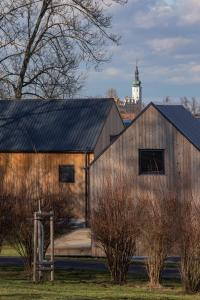 a wooden barn with a clock tower in the background at PRIMÁTOR CAMPING RESORT LITOMYŠL in Litomyšl