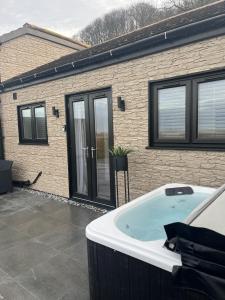 a hot tub in front of a house at Terfyn Hall holiday Apartment 2 in Prestatyn