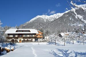 una casa nella neve di fronte a una montagna di Gästehaus Lindermuth a Presseggersee