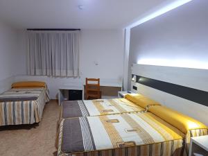 una habitación de hotel con 2 camas y una silla en Hostal Restaurante El Castillo, en Alcorisa