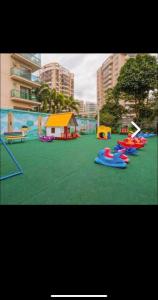 un parque infantil con varios juguetes inflables en la hierba en Apartamento no Joia da Barra, en Río de Janeiro