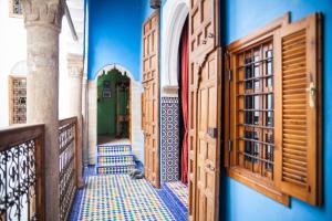 an alley with blue walls and wooden doors at Dar Shaeir in Rabat