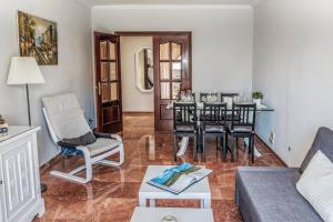 uma sala de estar com um sofá, uma mesa e cadeiras em Apartamento New Folch Sevilla A em Sevilha