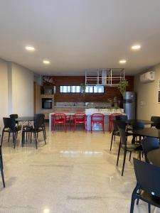 uma sala com mesas e cadeiras vermelhas e uma cozinha em Corais do Mar 204 Novo na Jatiúca em Maceió