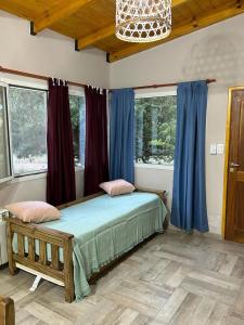 um quarto com uma cama num quarto com janelas em Cabañas del Arroyo Villa Ventana em Villa Ventana