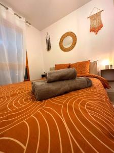 a bedroom with a large bed with an orange comforter at La plaine paisible - 15’ Paris 10’ Stade de France in Saint-Denis