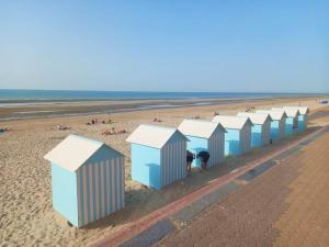 a row of blue and white beach huts on a beach at Julie's Home in Bray-Dunes