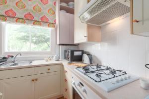 a kitchen with a stove and a sink at Charming flat in leafy West London by UnderTheDoormat in London