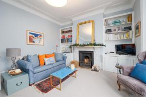 a living room with a blue couch and a fireplace at Charming flat in leafy West London by UnderTheDoormat in London