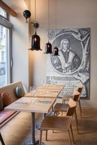 een eetkamer met houten tafels en een schilderij aan de muur bij Emmerich Hotel Görlitz in Görlitz