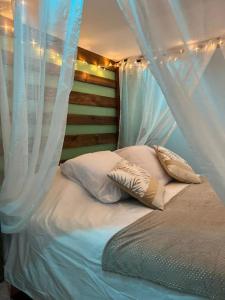 a bed with white curtains and pillows on it at ESCAPE ZEN Oasis tropicale & Spa privatif in Loon-Plage