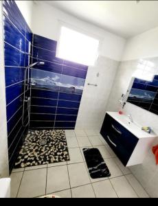 a bathroom with a sink and a shower with blue tiles at Villa aka merlot in Le Moule