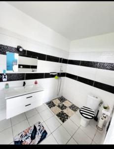 a bathroom with a black and white tiled wall at Villa aka merlot in Le Moule