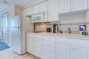a kitchen with white cabinets and a white refrigerator at Daytona Beach Resort 803 in Daytona Beach