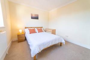 1 dormitorio con 1 cama con sábanas blancas y almohadas de color naranja en Much loved home with a view., en Poole