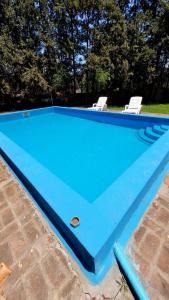 una piscina azul con 2 sillas en un patio en Casa Quinta Los Prados en Río Tala