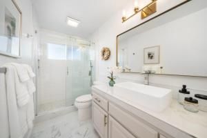 a white bathroom with a sink and a mirror at Steps Away From Pismo Beach with Poker, Foosball, FREE EV Charger, and Bikes in Oceano