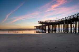 un muelle en la playa con gente en el agua en Steps Away From Pismo Beach with Poker, Foosball, FREE EV Charger, and Bikes, en Oceano