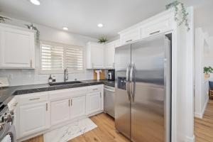a kitchen with white cabinets and a stainless steel refrigerator at Steps Away From Pismo Beach with Poker, Foosball, FREE EV Charger, and Bikes in Oceano