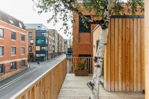 a wooden fence next to a tree on a street at Carmen Eco-Pod / Treehouse, Close to Cabot Circus in Bristol