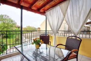 a glass table and chairs on a balcony with windows at Vavilato Home Kouramades in Kouramádes