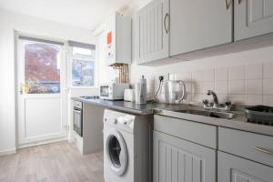 een keuken met een wasmachine en een wastafel bij Lovely 1 bedroom maisonette close to Airport, Town and Train Station in Luton