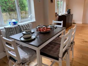 a dining room table and chairs with food on it at Cosy Cottage in the heart of Black Down Hills in Yarcombe