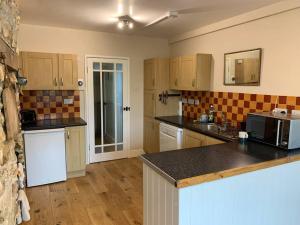 a kitchen with wooden cabinets and a counter top at Cosy Cottage in the heart of Black Down Hills in Yarcombe