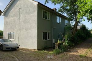 ein grünes und weißes Haus mit einem Auto vor dem Haus in der Unterkunft Cosy Cottage in the heart of Black Down Hills in Yarcombe