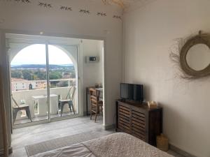 a bedroom with a bed and a television and a balcony at Hôtel Paradis in Bormes-les-Mimosas