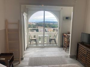 a room with an open door to a balcony with a table and chairs at Hôtel Paradis in Bormes-les-Mimosas