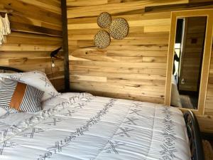 a bed in a room with a wooden wall at Bourbon Barrel Cottages #2 of 5 on Kentucky trail in Lawrenceburg