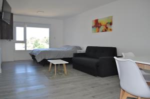 a living room with a black couch and a bed at Edificio Frente al Mar - Amplios departamentos in Caleta Olivia