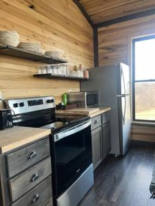 a kitchen with a stove and a refrigerator at Bourbon Barrel Cottages #2 of 5 on Kentucky trail in Lawrenceburg