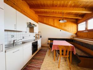 cocina con mesa y cocina con armarios blancos en Apartment Oberhauserhof, en Falzes