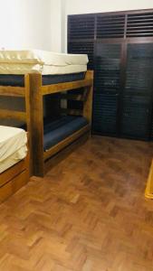a room with two bunk beds and a wooden floor at Apartamento frente ao mar Pitangueiras in Guarujá
