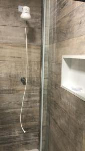 a shower with a glass door with a light on it at Apartamento frente ao mar Pitangueiras in Guarujá