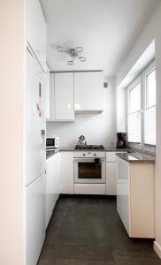 a white kitchen with white appliances and a ceiling fan at Apartament Gallusa in Katowice